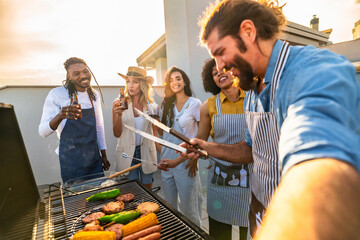 Friends grilling food and taking selfie on rooftop at sunset