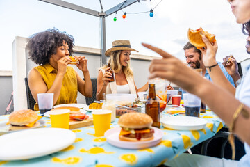 Friends eating burgers and drinking beer at rooftop party