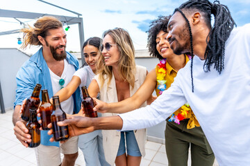 Friends toasting with beer bottles at rooftop party