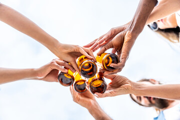 Friends toasting with beer bottles in the sky