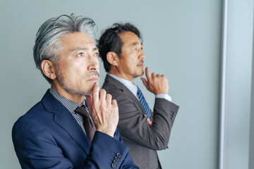 考えるミドルエイジ男性ビジネスパーソンのグループ