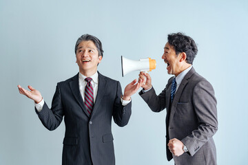 A middle-aged male business person calling out to middle-aged and elderly men through a loudspeaker