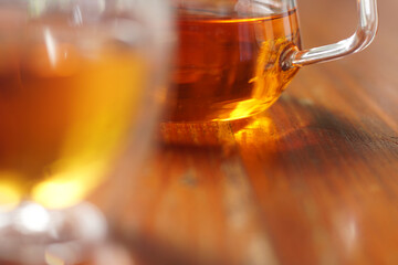Tea time. Pouring black tea into glass cup on wooden table. Close up, top view of hot tea in transparent glass.	