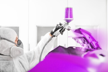 Spray painter worker in protective glove with airbrush pulverizer painting car element in white...