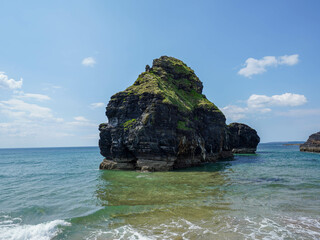 A large rocky island covered with grass rises from the blue sea