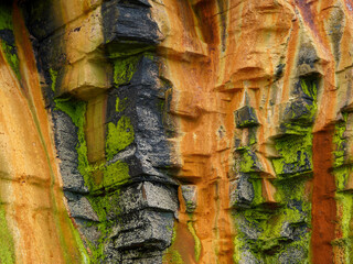 Layered rock formation with orange yellow black and green colors