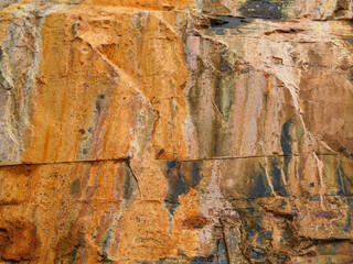 The surface of the rock shows colorful mineral layers and cracks