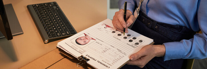 Middle aged Caucasian woman filling out criminal profile form with mugshot and fingerprints,...
