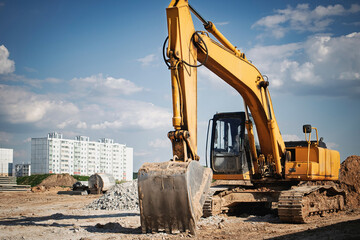 Excavator working on construction site in urban area under blue sky and fluffy clouds