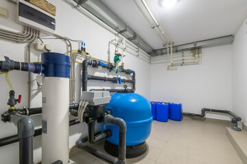 A well-organized water treatment facility features a blue storage tank connected to multiple pipes....