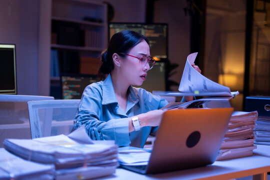 Working Asian women feel stressed,tired from work,migraine headaches from hard work while working and overtime in office at night
