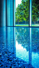Obraz premium Modern glass door with view of green trees and reflections on polished terrazzo floor