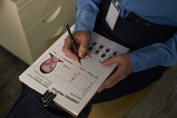 Middle aged Caucasian woman filling out criminal profile form with mugshot and fingerprint records,...
