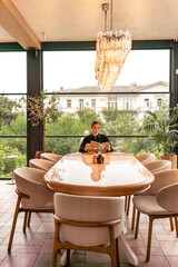 Restaurant menu chandelier: Woman reads menu in luxury restaurant in daylight, choosing meals.