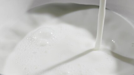 Milk is streaming and splashing leaving beautiful round ripples on the milk surface. Slow motion close up video - Powered by Adobe