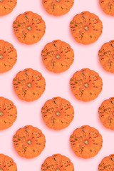 Repetitive pattern made of small orange pumpkin on a pink background.