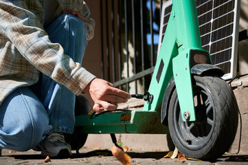 Close-up of woman hands connecting solar panel to electric scooter, highlighting sustainable...