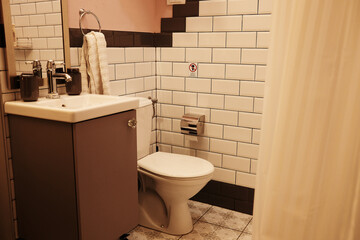 View of a small modern bathroom with white sink, chrome faucet, mirror, toilet and decorative tiled...