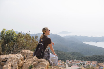Naklejka premium Young woman enjoying peaceful solo travel scenic mountain and sea views. Mindful moment of digital detox, eco-tourism, and personal reflection in nature. Concept of freedom and intentional living.