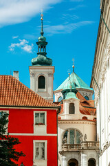Spires and domes rise above the vibrant rooftops under a blue sky in Prague, Czech Republic.