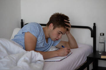 Teen boy writing in bed in the morning. _Morning Thoughts Collection
