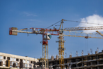 A crane in front of a building under construction. The sky is clear and blue. construction of a...