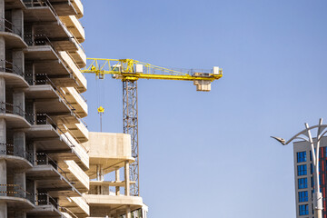 High rise building under construction in evening sky. The construction and tower crane at sunlight...