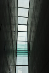 Modern concrete corridor with glass ceiling and bridge, showcasing minimalist industrial...