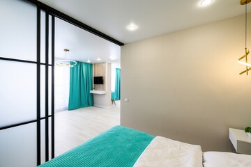 Modern bedroom with teal accents, frosted glass partition, and a stylish lamp. Neutral wall paint...