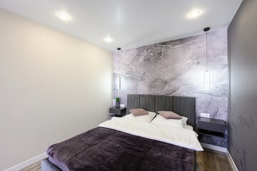 modern bedroom features a gray upholstered bed with white linens, dark brown blanket and mauve...
