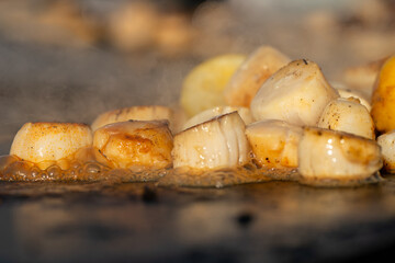 Nourriture variée en train de cuire sur une plancha extérieure, avec vapeur et grillades...