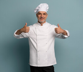 cooking, culinary and people concept - happy smiling mature male chef showing thumbs up over blue