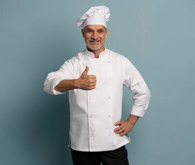 cooking, culinary and people concept - happy smiling mature male chef showing thumbs up over blue