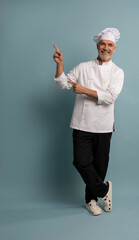 Mature male chef presenting something over blue background.
