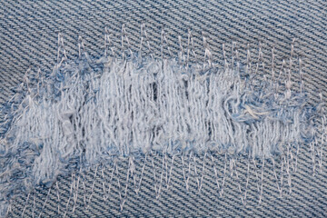 Closeup detail of torn on blue jeans. Denim jeans texture.
