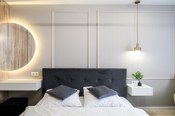 modern bedroom scene featuring a bed with dark headboard, white bedding, floating bedside tables,...