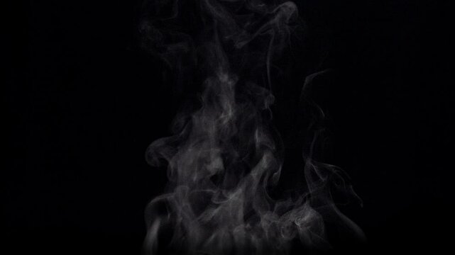 White natural rising steam from food or hot drink isolated on a black background.