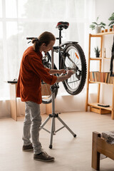 Bicycle repair DIY. Young man using tools to fix bike wheel at home. Bicycle maintenance and wheels...
