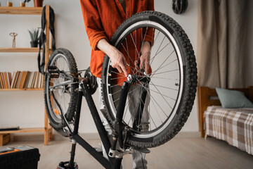 Young man fixing his bicycle at home using a spanner fix wheels, close-up