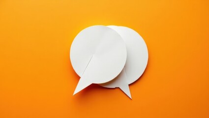 Burbuja de diálogo de origami de papel sobre un fondo naranja brillante, que simboliza el diálogo creativo y la colaboración empresarial