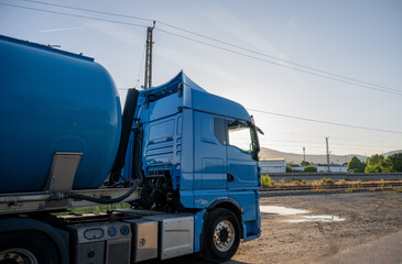 semi truck with tanker parked near railway tracks at sunset, representing transportation logistics
