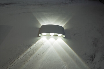 A white wall light is shining on a white wall
