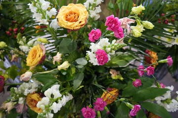 Vibrant floral arrangement with yellow-orange roses, pink carnations, white snapdragons, and...
