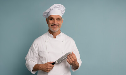 Portrait of a happy male chef cook holding knife isolated on a blue background