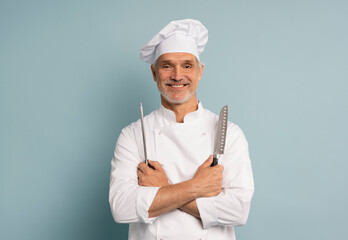 Portrait of a happy male chef cook holding knife isolated on a blue background