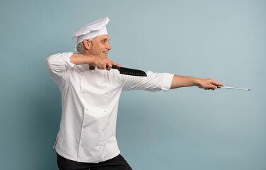 Portrait of a happy male chef cook holding knife isolated on a blue background