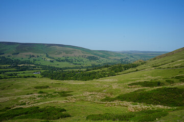 Obraz premium A scenic landscape view of a lush, green valley with rolling hills and scattered trees, creating a peaceful countryside feel.