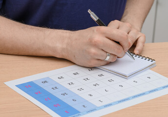 Young man writing down exam date in calendar, life planning personal development and career path,...
