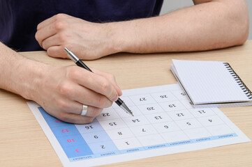 Man writing down important dates in calendar, life organization