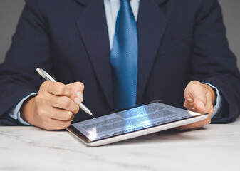 Businessman signing digital document on tablet with stylus, symbolizing e-signature process.